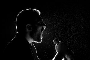 Profile of a man singing into a microphone