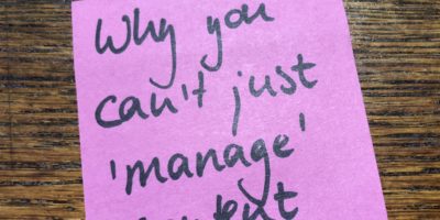 Pink post-it with 'why you can't just 'manage' content written on it in black ink.