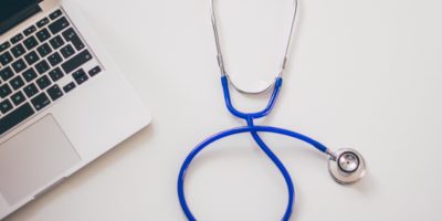 A stethoscope on a table next to a laptop