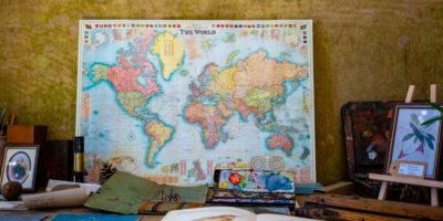 A map of the world on a desk propped up against a wall.