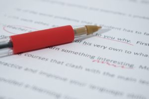 A red ballpoint pen lying on a page of writing.